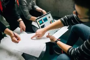 Three people having a meeting and one person pointing at a piece of paper.