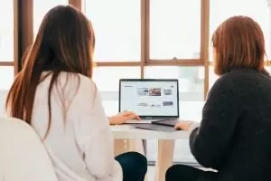 two women looking at a website on a laptop