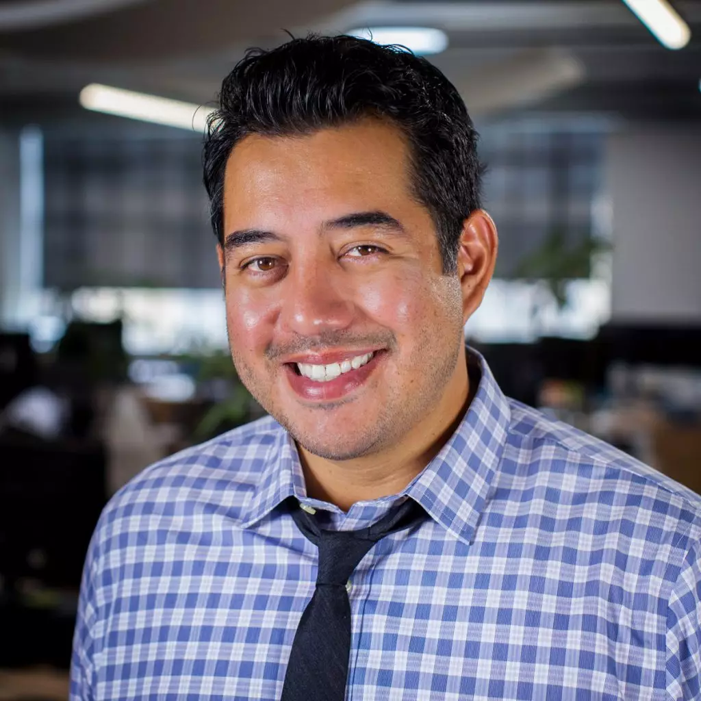 A man smiles while standing in an office