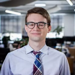 A man smiles while standing in an office