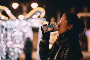 side profile of woman sipping a to-go coffee cup with a snowman on it