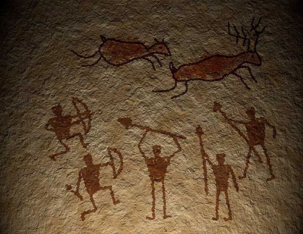 Brown colored cave drawings of people holding spears chasing animals.