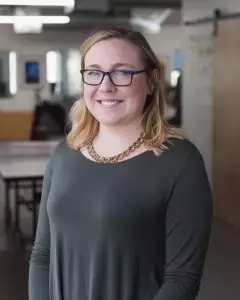 Woman wearing a charcoal colored blouse smiling at the camera.