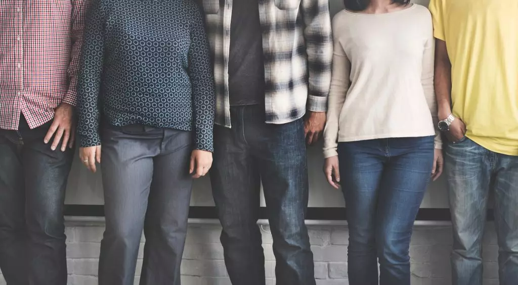 Five people in jeans looking at the camera with their heads cropped out of the image.