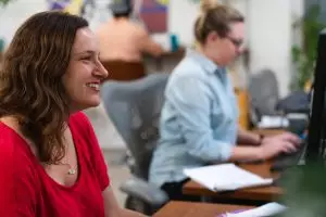 Two female SEO marketers working at their desks in an office.