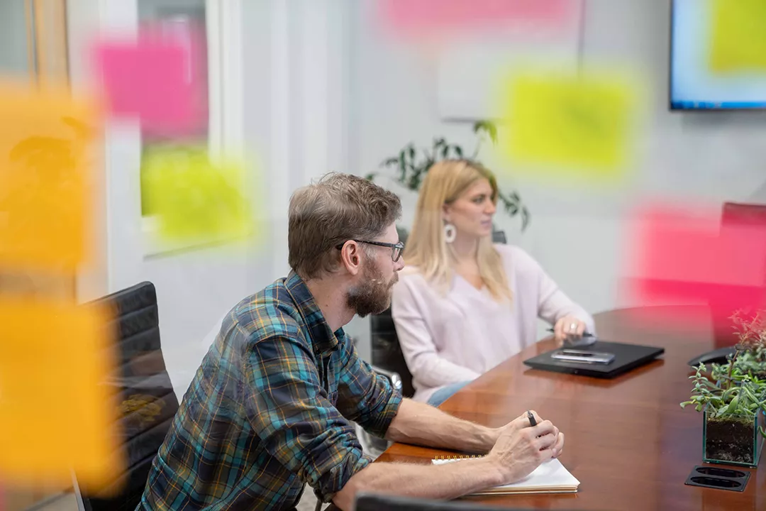 Two marketing experts discuss process, with sticky notes in the foreground