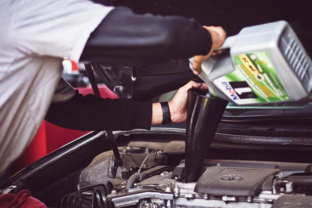 Eastwood Auto Body employee adds oil to a vehicle