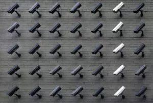 Cameras in rows, mounted on a wall. 6 rows of black cameras and 1 row of white cameras