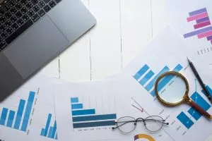 Computer on desk along with several printed bar graphs for market research