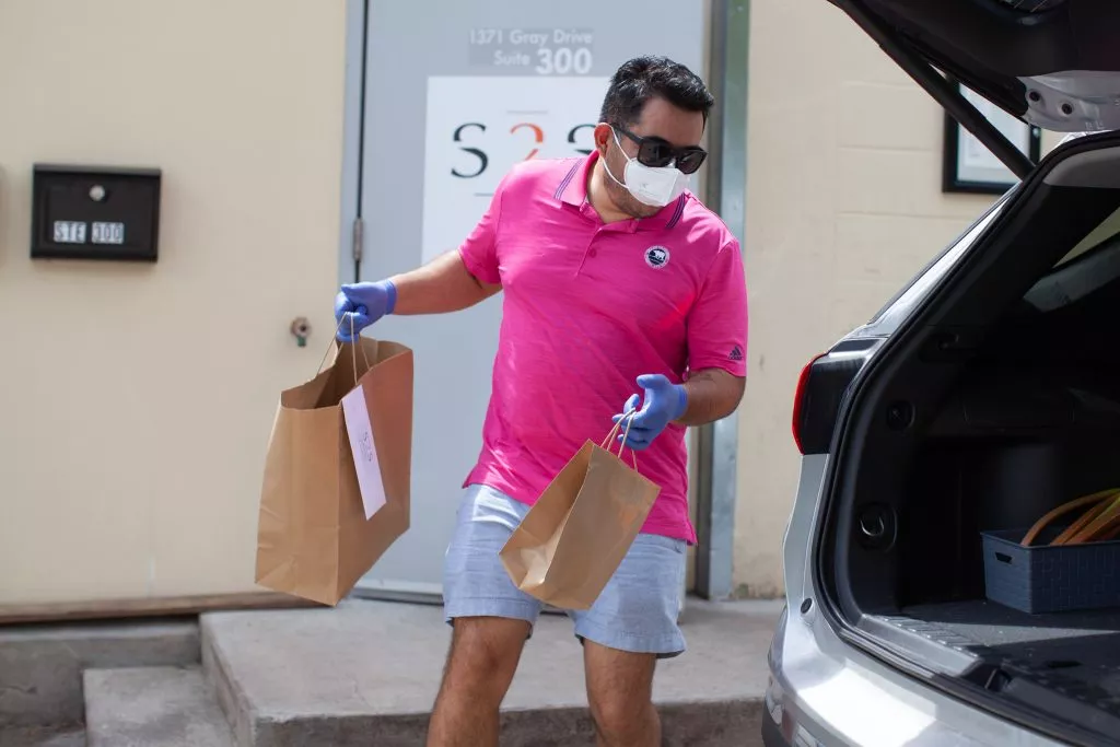 Oneupweb CEO loading paper bags into the back of a car for employees working remotely