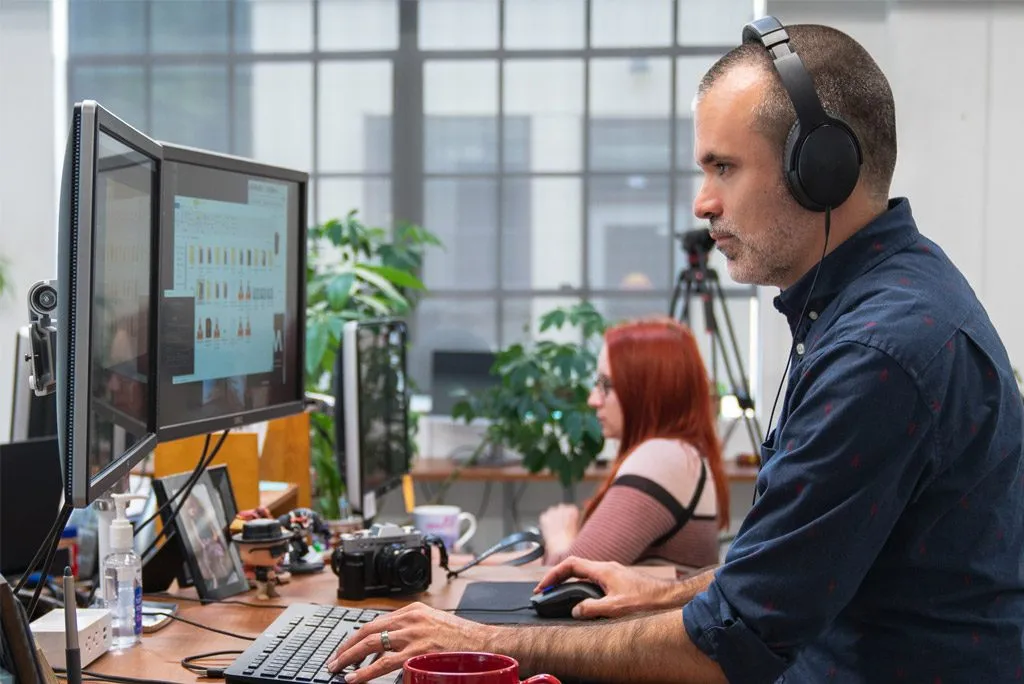 Video editor wearing headphones editing on a computer.