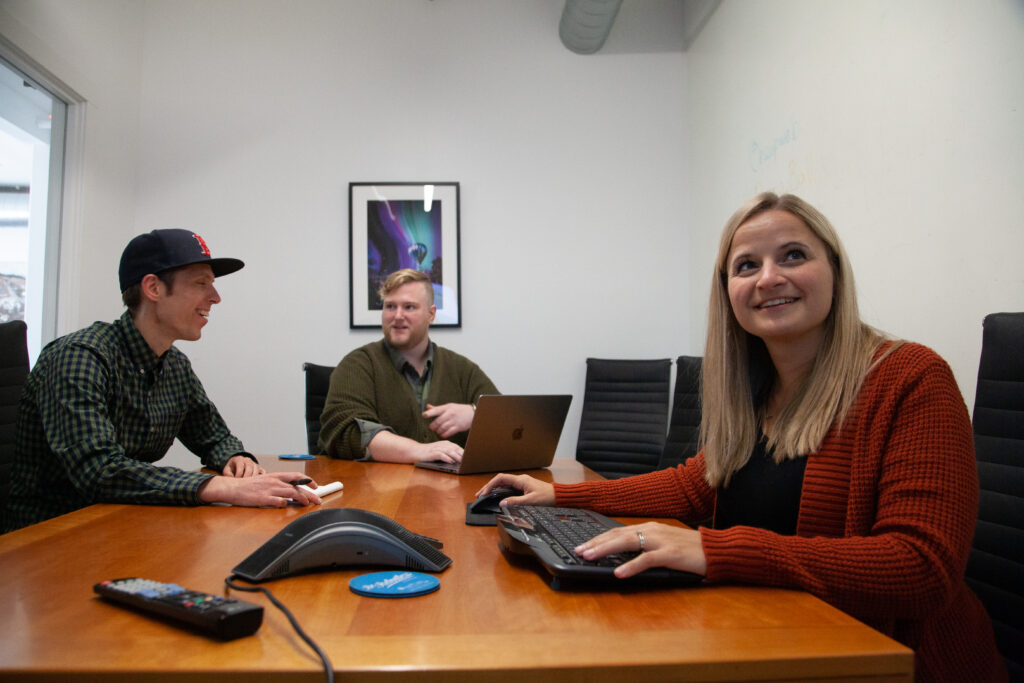 three content marketers look at a computer screen in a meeting room