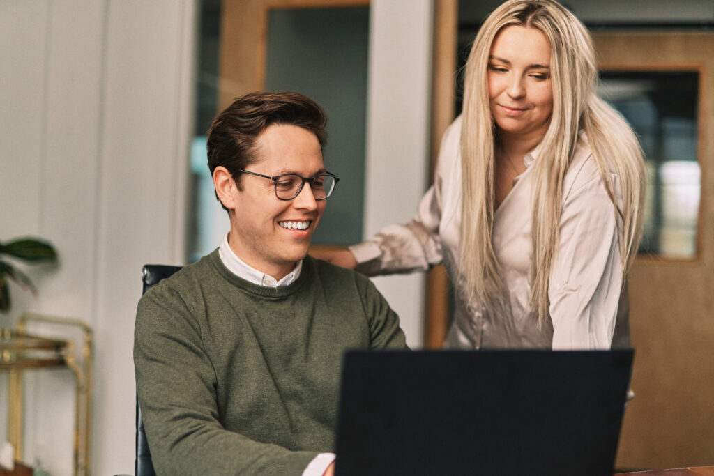 two marketers work on a laptop in an office setting