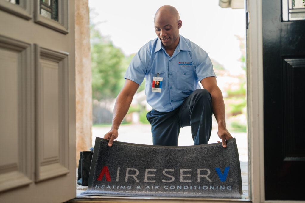 an aire serv employee laying a rug down in the home entryway